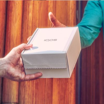 Une personne remettant une boîte IQOS.