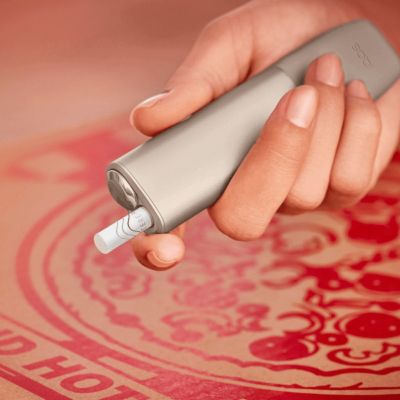 Someone is holding a silver IQOS ILUMA PRIME Holder.