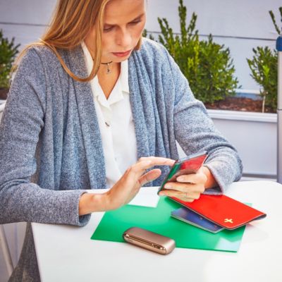 Mujer en el celular con IQOS ILUMA sobre la mesa