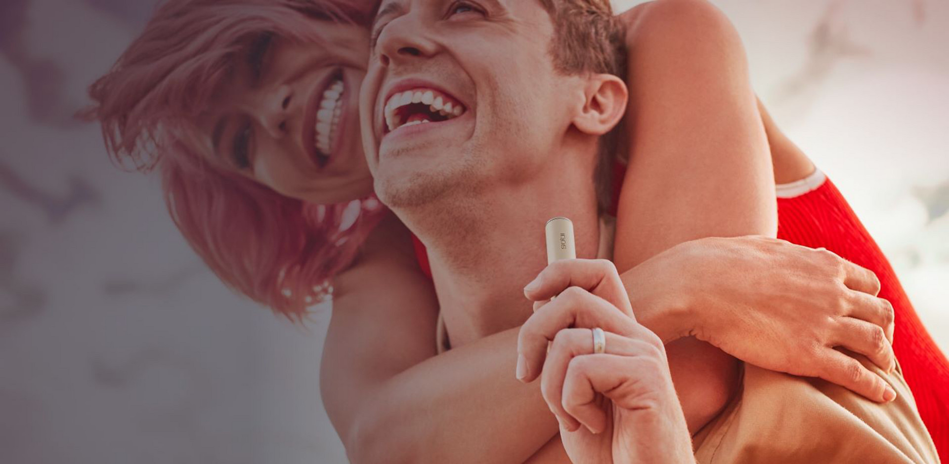 Usmívající se pár, muž drží v ruce zařízení IQOS ILUMA