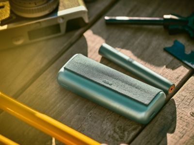 A couple taking a walk; one using an IQOS device.