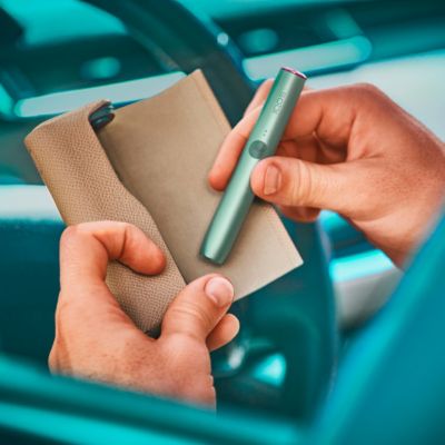 Hände stecken IQOS Halter Jade Grün in Charger mit Leder Cover