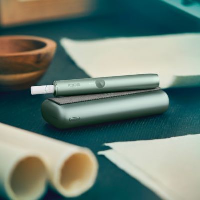 An IQOS device on a desk next to papers.