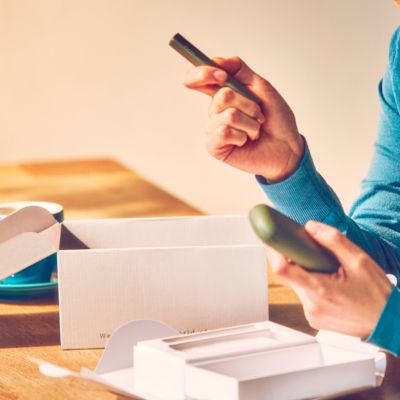 Seseorang yang memegang Pocket Charger dan Holder IQOS ILUMA.