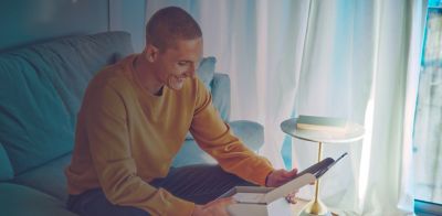 A man sitting on his sofa smiles as he unboxes his newly bought IQOS ILUMA device