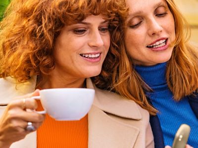 Usuarios de IQOS disfrutando un té mientras miran su móvil. 