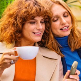 Black IQOS 3 device and mobile phone in two people's hands