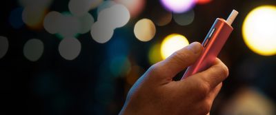 Person holding IQOS ILUMA i Holder with tobacco stick inserted