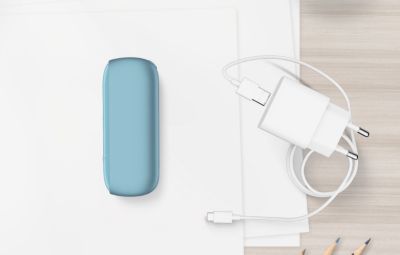 Chargeur de poche turquoise IQOS ORIGINALS DUO à côté du chargeur de câble.