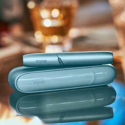 IQOS Originals Duo en turquoise sur une table basse brillante.