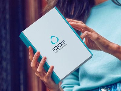 Femme ouvrant une boîte IQOS livrée à son domicile
