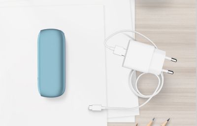 Chargeur de poche IQOS ORIGINALS DUO en turquoise à côté du chargeur et de câble USB.