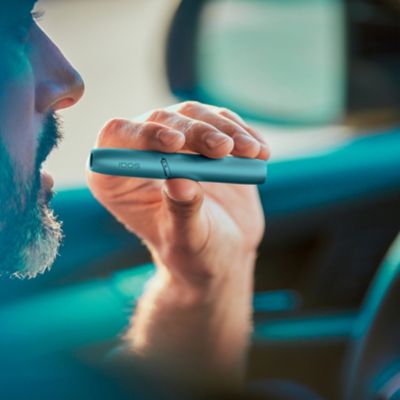 Man holding IQOS Originals Duo holder in the car