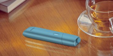 Aufnahme eine Tisches mit einem Teegetränk und einem IQOS Originals One.