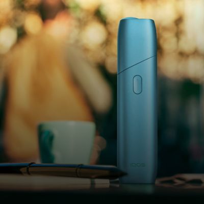 Stylet et chargeur de poche IQOS 3 DUO bleu, dans la main d'un homme d'affaires.