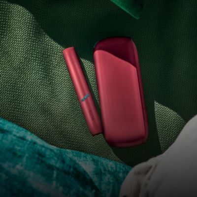 Brilliant gold IQOS 3 DUO with HEETS stick on top of charger