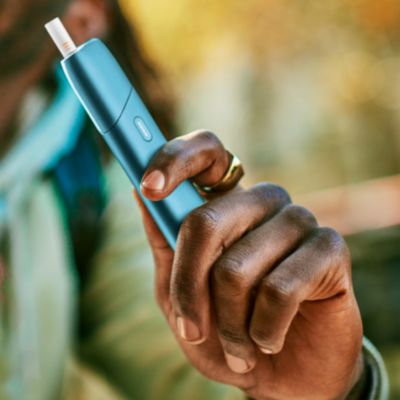 Hand holding a turquoise IQOS Originals One device 