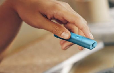 Main tenant un IQOS Originals ONE en turquoise.