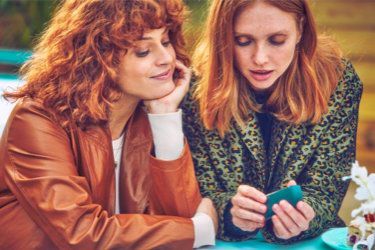 A gold IQOS device in its holder in a person's hand.