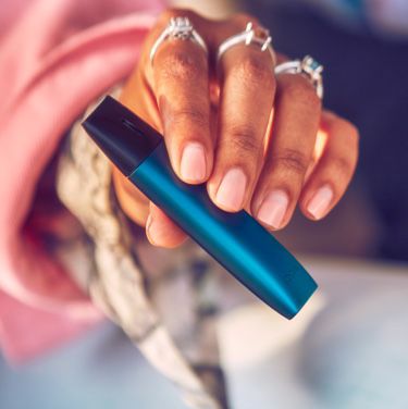 A couple smiling; the man holding an IQOS VEEV device.