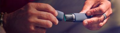 Cap of IQOS VEEV taken off in the hands of a man