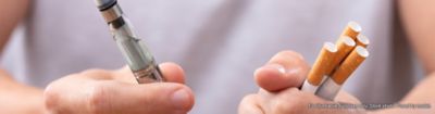 Man holding vape and cigarettes