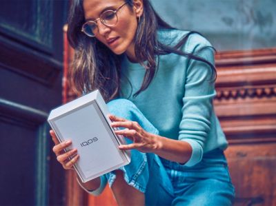 Manos utilizando una consola de sonido mientras sostienen un IQOS ILUMA