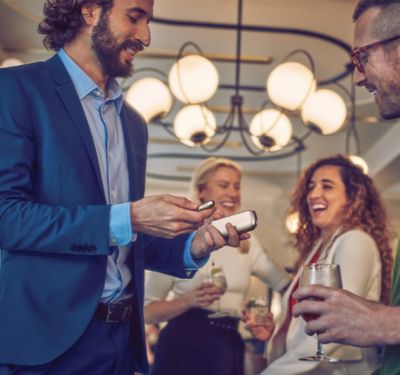  Friends toasting with wine; IQOS users can provide a referral code to purchase the starter kit with benefits.