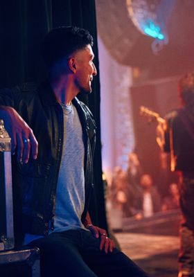 Hombre sentado en un concierto mirando al guitarrista