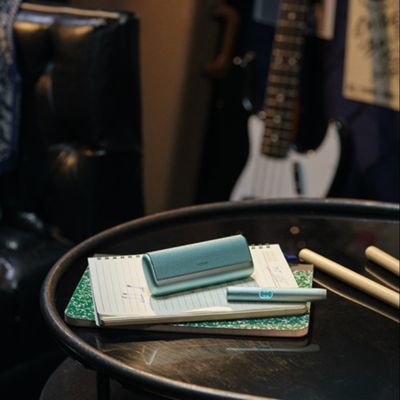 IQOS ILUMA i PRIME color Breeze Blue al lado de un café