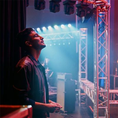 Persona apoyada en la pared en la parte trasera de un concierto