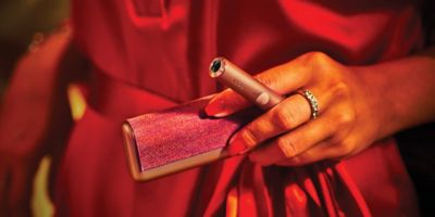 جهاز IQOS ILUMA i PRIME باللون النبيتي فوق شاحنه