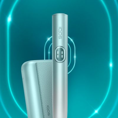 Устройство IQOS ILUMA i PRIME цвета Лазурный бриз и зарядное устройство на темно-бирюзовом фоне