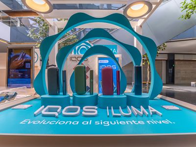Dispositivos IQOS ILUMA dentro de exhibidor circular con fondo desenfocado.