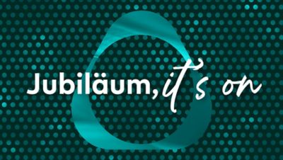 Zwei IQOS ORIGINALS Geräte vor dunkelgrünem Punktemuster.