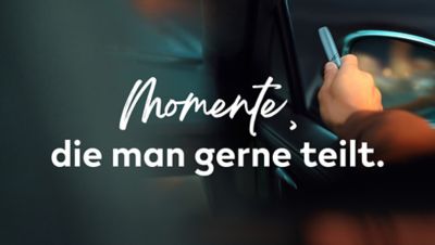 Eine Hand hält ein IQOS Gerät nahe einem Autofenster, darüber steht der Text „Momente die man gerne teilt".