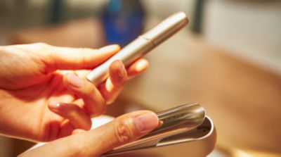Woman with a golden IQOS holder and charger in her hand