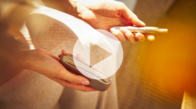 Woman showing a golden IQOS holder and charger in her hand