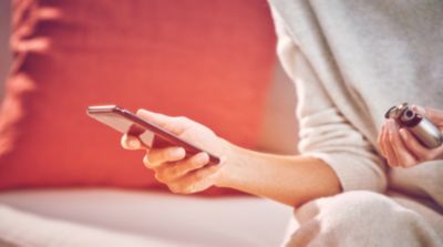 Woman checking her mobile with a IQOS kit in her hand