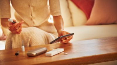 Woman with a IQOS holder in her hand and other accessories on a table