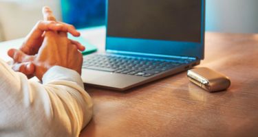 Man using his laptop with his IQOS device on the table