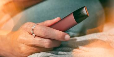 A hand giving a gold IQOS VEEV 