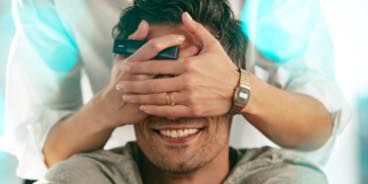 Person covering someone else eyes and holding an IQOS VEEV