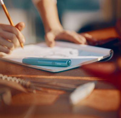 Dispositivo IQOS ILUMA i PRIMERA GENERACIÓN color turquesa sobre una mesa mientras una persona escribe.