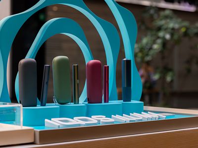 Primer plano de dispositivos IQOS ILUMA dentro de exhibidor circular turquesa.