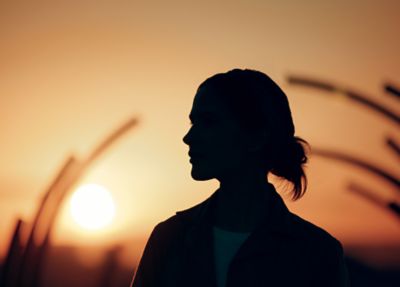 Silueta de mujer al atardecer sin dispositivo visible.