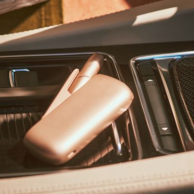 Appareil IQOS gold sur l’élément central d’une voiture