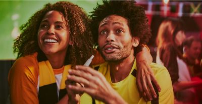 Fans in a sports bar, one using an IQOS device.