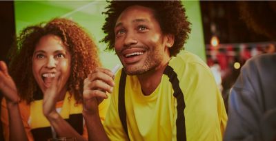 مشجِّعون في نادٍ رياضي، وأحدهم يستخدم جهاز IQOS. 