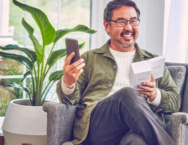 Un hombre sonriente sosteniendo un dispositivo IQOS.